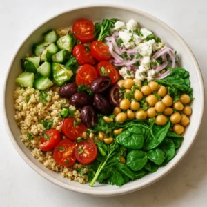 Mediterranean quinoa bowl with cucumber, tomatoes, chickpeas, feta, herbs, and toasted pine nuts